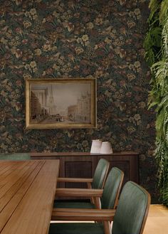 a wooden table with green chairs in front of a painting on the wall behind it