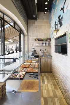 the inside of a restaurant with lots of pizzas on the counter and in front of an open window