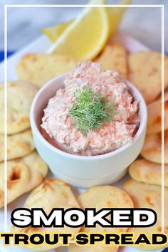 a white plate topped with crackers and a small bowl filled with smoked trout spread