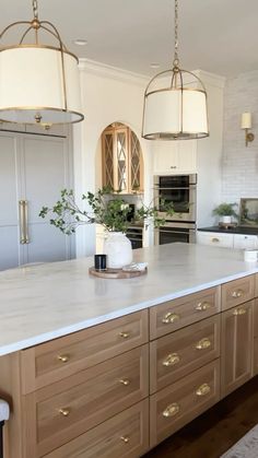 a large kitchen island with two hanging lights above it and an oven in the background