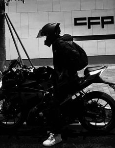 black and white photograph of a person sitting on a motorcycle with the back turned to the camera