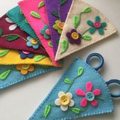 four different colored felt flowers and scissors on a table