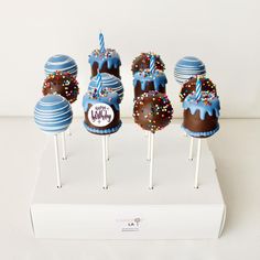 chocolate covered cake pops with blue frosting and sprinkles are on a white stand