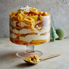 a layered cake on a glass stand with a spoon next to it and some other food items