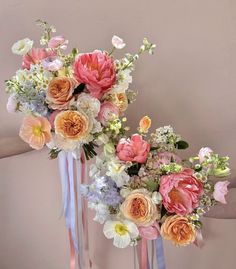 two bouquets of flowers are on display in front of a wall with pink and blue ribbons