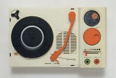 an old fashioned radio with orange and black trimmings on the front, sitting on top of a white surface