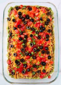 a casserole dish filled with black olives, tomatoes and cheese