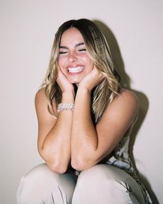 a woman sitting on the floor with her hands behind her head and smiling at the camera