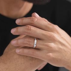 a close up of a person wearing a wedding ring on their left hand, with his right hand resting on the other hand