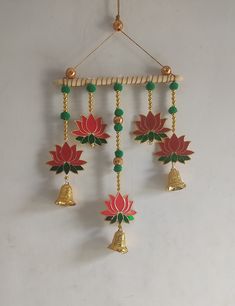 a wall hanging decoration with bells and flowers on it's side in gold, green and red