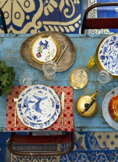 the table is set with blue and white plates, silverware, and other items