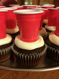 cupcakes with white frosting and red cups on top are sitting on a plate