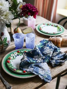 a wooden table topped with plates and napkins