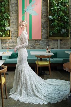 a woman in a white wedding dress standing in front of a wall with birds on it