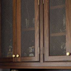 a wooden cabinet with glass doors and gold handles