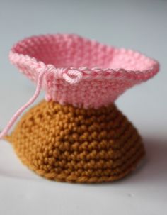 a small crocheted pot holder with a pink and brown cover sitting on a white surface