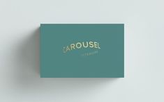 a close up of a business card on a white surface with the word carousel written in gold