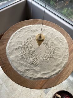 a wooden table with a white rug on top of it and a light hanging from the ceiling