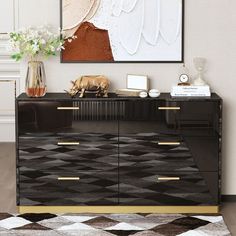 a black and gold sideboard in a living room next to a painting on the wall