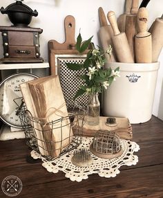 an assortment of kitchen utensils and cutting boards on a wooden table with lace doily