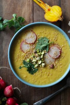 a bowl of soup with radishes, nuts and cilantro on the side