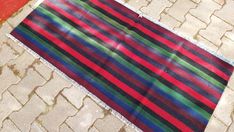 a multicolored striped rug laying on the ground