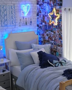 a bed with blue sheets and pillows in a room that has pictures on the wall