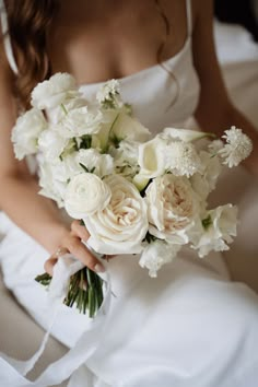 a bride holding a bouquet of white flowers