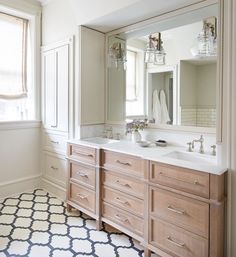 a large bathroom with two sinks, mirrors and cabinets in the middle of the room