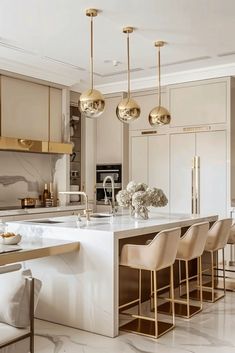 an elegant kitchen with marble counter tops and gold pendant lights hanging from the ceiling over the island