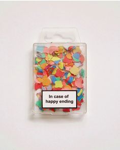 a plastic container filled with colorful confetti and a sign that says in case of happy ending