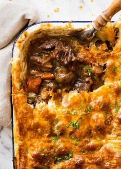 a casserole dish with meat and vegetables in it on a white tablecloth