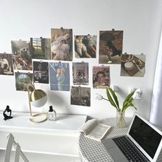 a laptop computer sitting on top of a white desk next to a vase filled with flowers