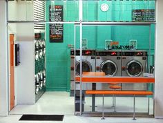 a washer and dryer in a room with blue tiles on the walls, an orange bench sits next to it