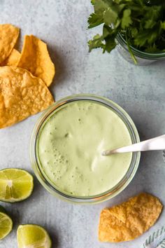 guacamole and tortilla chips on a table with lime wedges