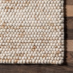 a white rug on top of a wooden floor next to a brown and white wall