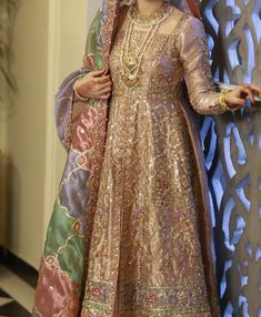 a woman in a bridal gown standing next to a wall with an intricate design on it