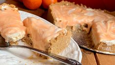 a piece of cake on a plate with a fork and some oranges in the background