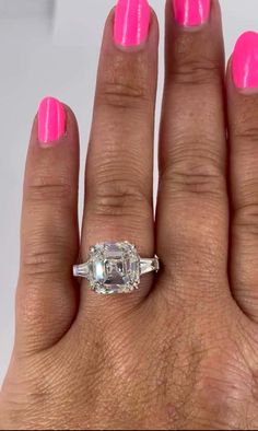 a woman's hand with pink nail polish and an engagement ring on her finger