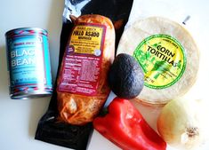 an assortment of food including tortillas, peppers and black bean sauce on a white surface