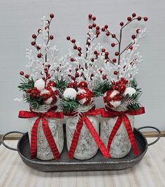 three decorated christmas stockings sitting on top of a metal tray with red and white ribbon