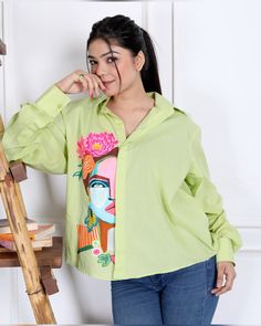 a woman standing in front of a ladder wearing a green shirt with an image on it