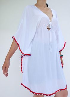 "🚚..ALL ORDERS ARE SHIPPED VIA DHL EXPRESS MAIL Opt for the perfect beach cover up with this white kaftan cut with kaftan sleeves, v-neck with drawstring tie closure and pom pom trim along edges. Layer it over your brightly color bikinis for a beach ready look. It's an irresistibly stylish choice for sun-soaked getaways. * Pull-on style * V-neck with drawstring tie closure * Kaftan sleeve. * Red, white and blue pom pom trim along edges * Ruched waistline detail at center front and center back * V-neck Beach Dress With Tassels For Vacation, Bohemian V-neck Kaftan For Vacation, Beachwear V-neck Cover-up With Tassels, Long Tasseled Kimono For Vacation, Bohemian White V-neck Cover-up, Red V-neck Kaftan For The Beach, Summer Beachwear Kaftan With Back Tassel Tie-up, Summer Long Kimono With Tassels, Red Kimono For Beach Cover-up