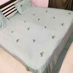 a bed with blue sheets and white flowers on it