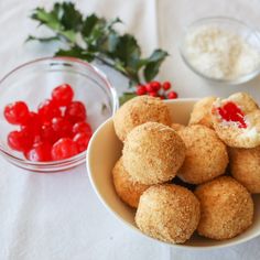 some food is in a bowl and on the table next to it are cherries