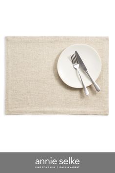 an empty plate with a fork and knife sitting on it next to a place mat that says annie selke