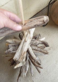 a person is holding sticks over some driftwood that has been placed on the floor