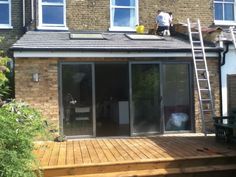 a man standing on top of a wooden deck next to a building with sliding glass doors