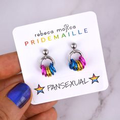 there is a pair of colorful earrings in the hand and it says pride malle