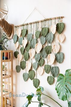 a wall hanging made out of leaves and other plants in a room with white walls